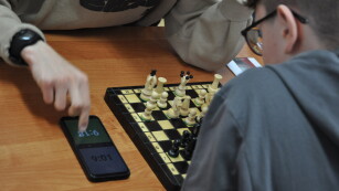 Uczestnicy grają w szachy, obok leży telefon z zegarkiem