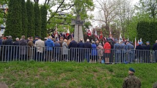 Grupa ludzi stojąca pod pomnikiem