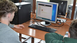 Uczniowie siedzą przy komputerze z otwartą stroną do testowania podatności sieciowych
