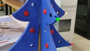 Złożona wydrukowana choinka w kolorze niebieskim z Czerwonymi Bombkami i Zielonym Mchem w podstawie.