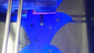 Część choinki w kolorze niebieskim w trakcie wydruku na drukarce 3D.