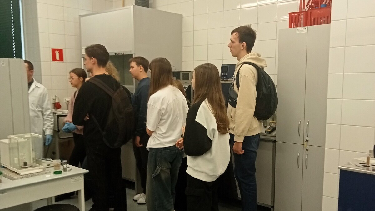 Uczniowie stojący przy sprzęcie laboratoryjnym.