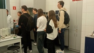 Uczniowie stojący przy sprzęcie laboratoryjnym.