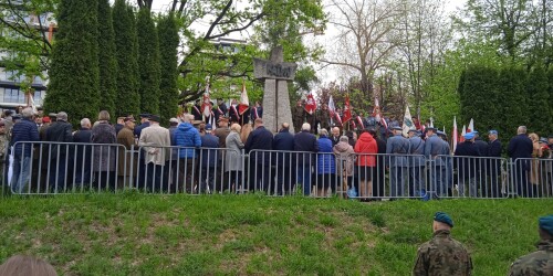 Grupa ludzi stojąca pod pomnikiem