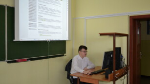 Uczeń siedzi przy komputerze, robi wykład o atakach sieciowych