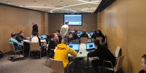 Grupa uczniów na sali przed laptopami